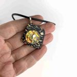 Dichroic stacked Pendant in hues of Gold in hand